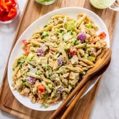 A platter of healthy tuna pasta salad with wooden serving spoons on the side.