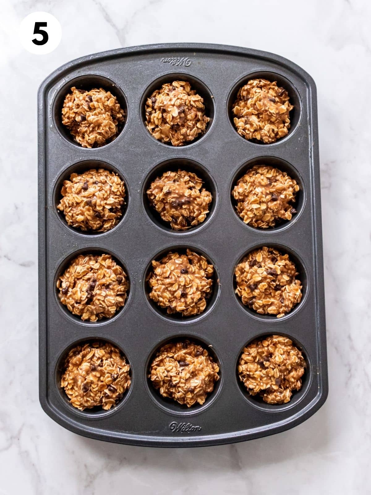 Banana peanut butter mixture separated into well in a muffin tin. 