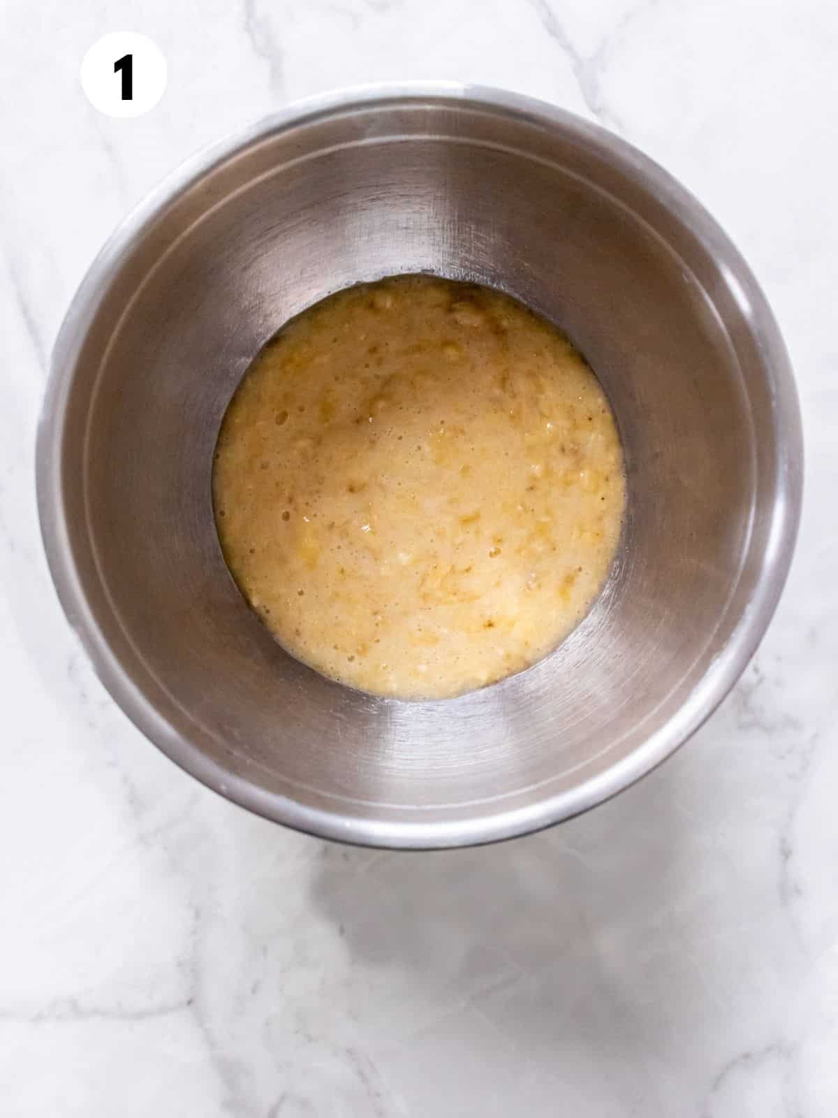 Mashed banana in a metal mixing bowl.