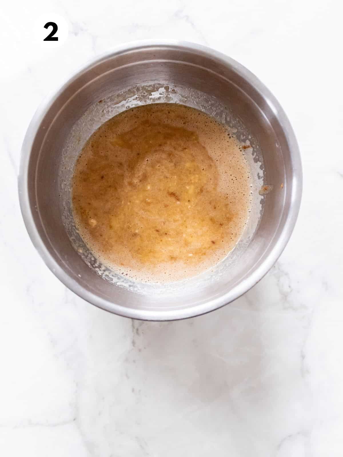 Wet ingredients for healthy banana peanut butter muffins in a metal mixing bowl.