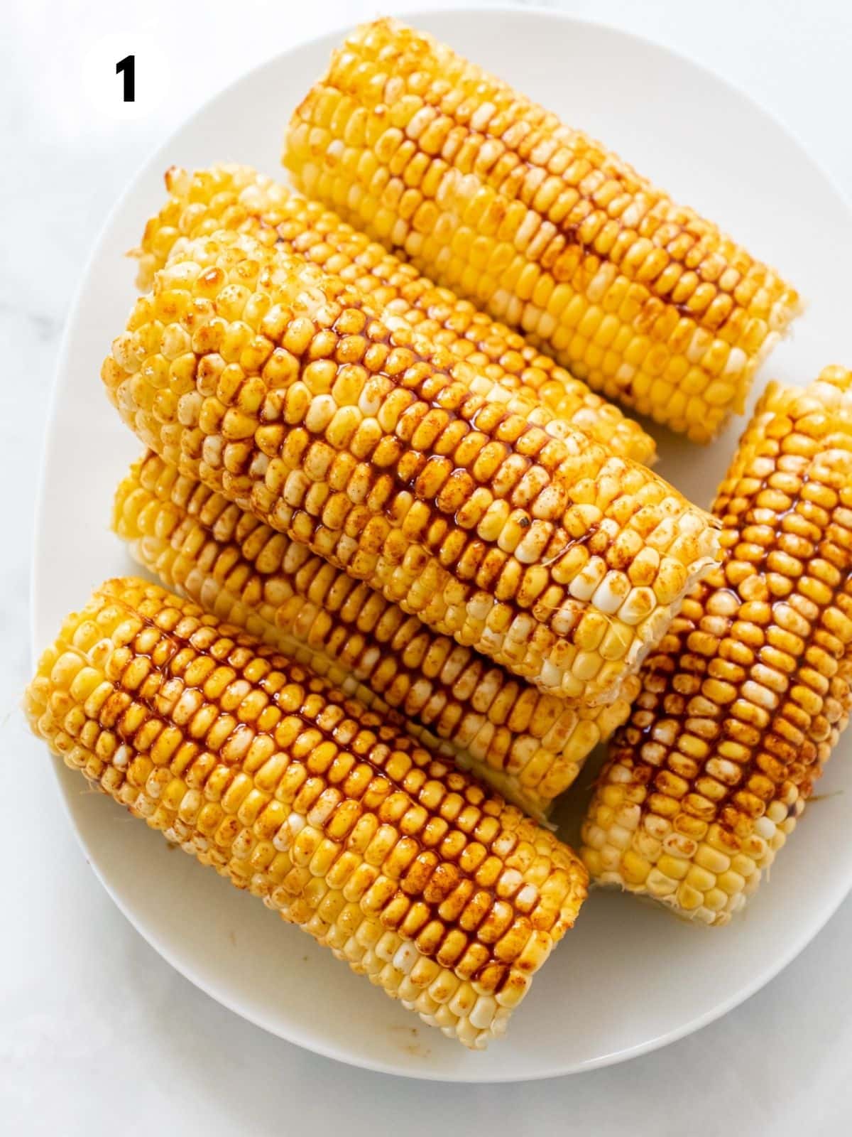 Seasoned, shucked corn sitting in a white bowl.