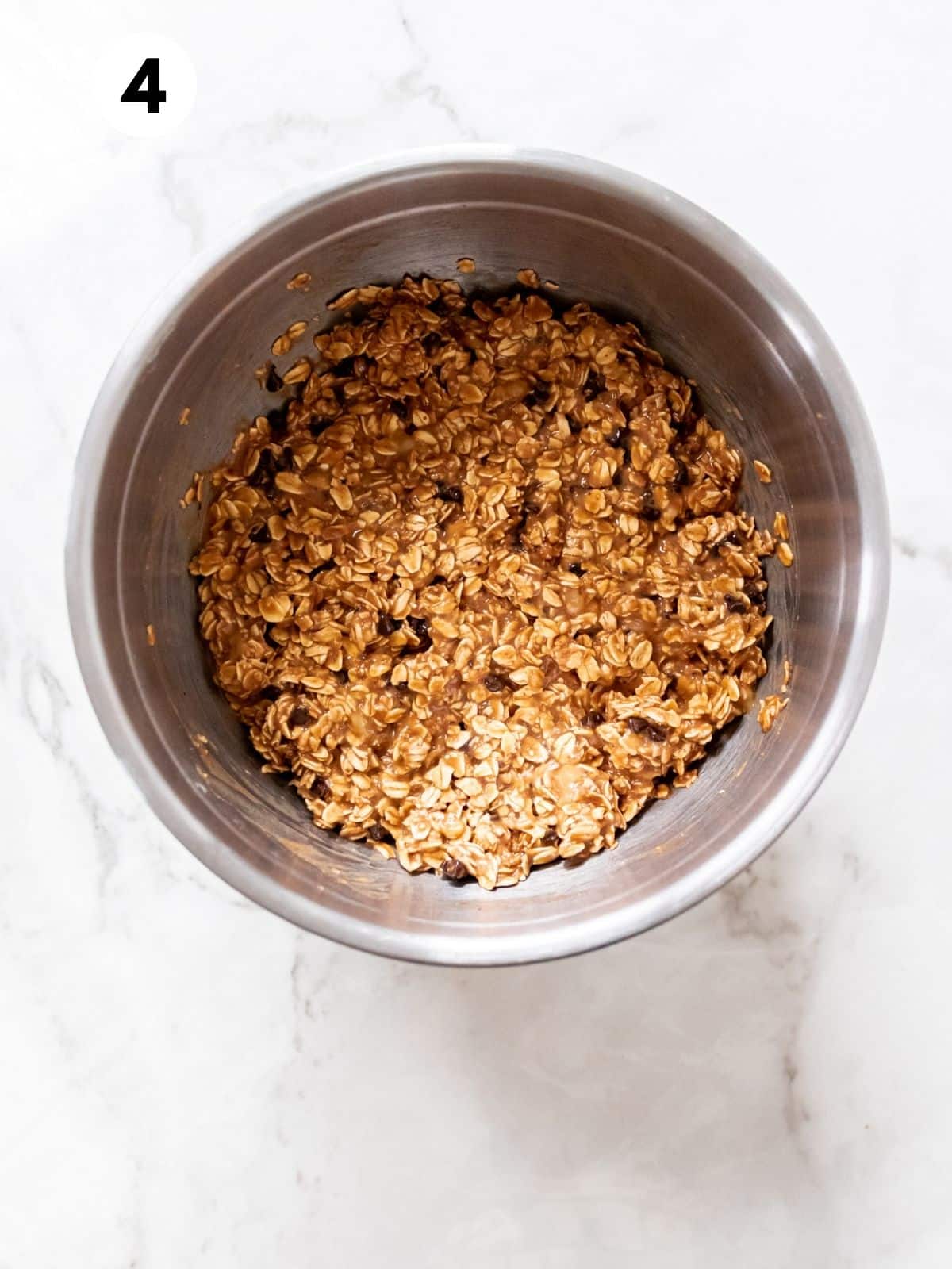Peanut butter banana muffin batter, with chocolate chips, combined in a metal mixing bowl.