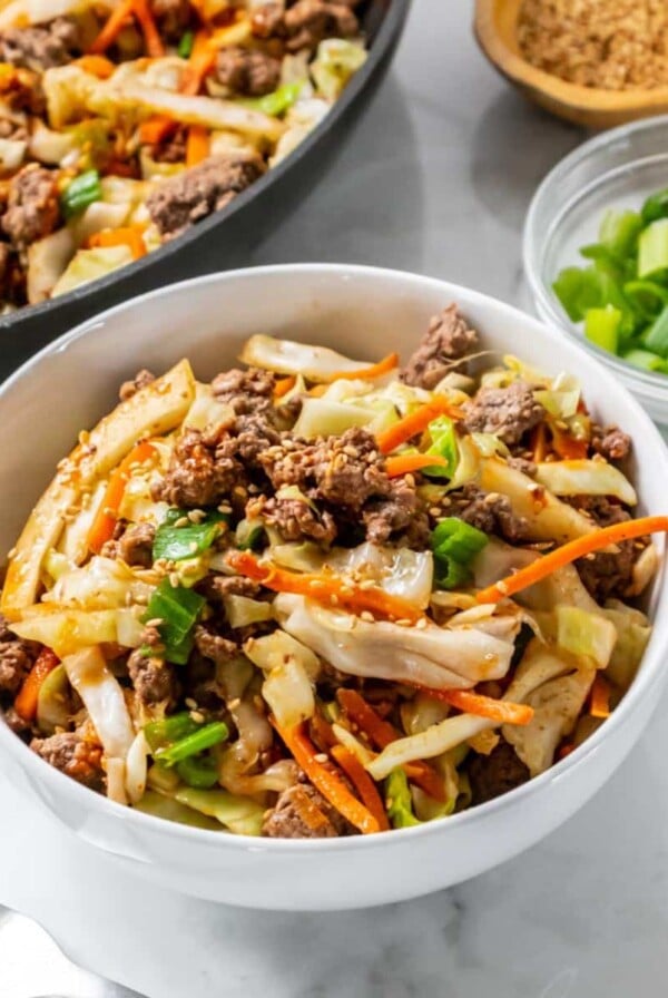 A beef cabbage bowl on the table with a skillet of more in the background.