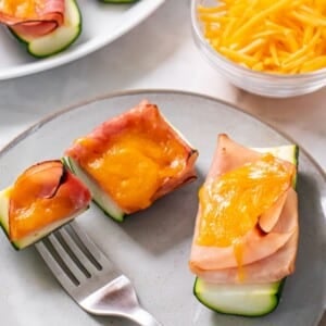 Healthy zucchini boats with lunch meat and cheese on a plate with a fork holding a bite.