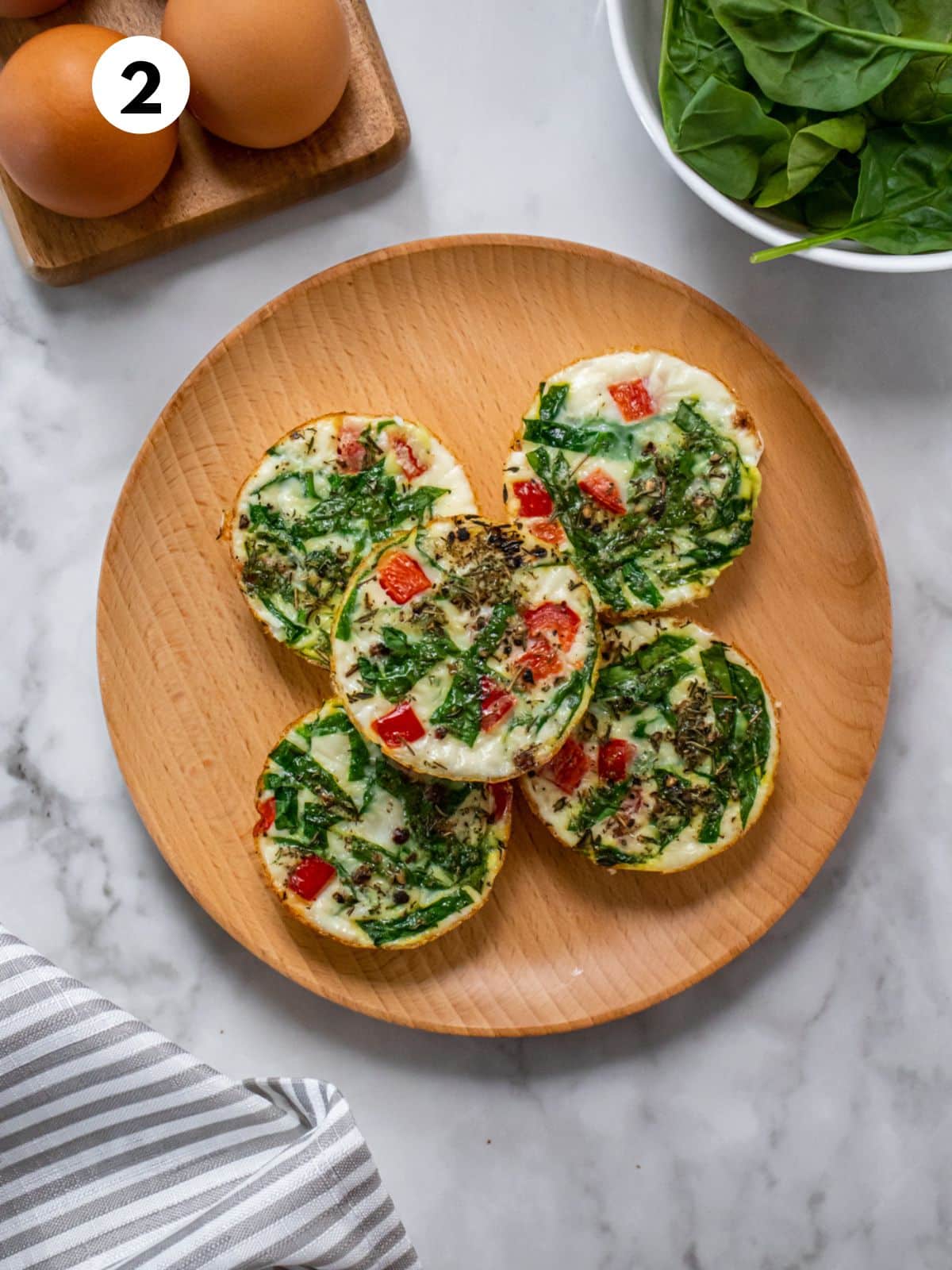 Egg white bites on a wooden round plate.