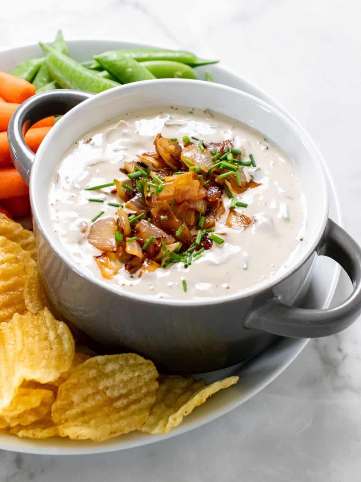 Healthy French onion dip served up in a bowl with fresh veggies and chips.