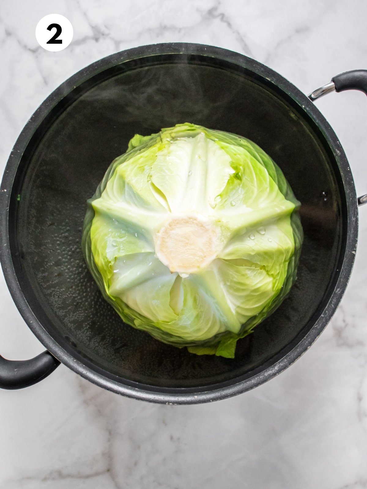 A head of cabbage cooking in water.