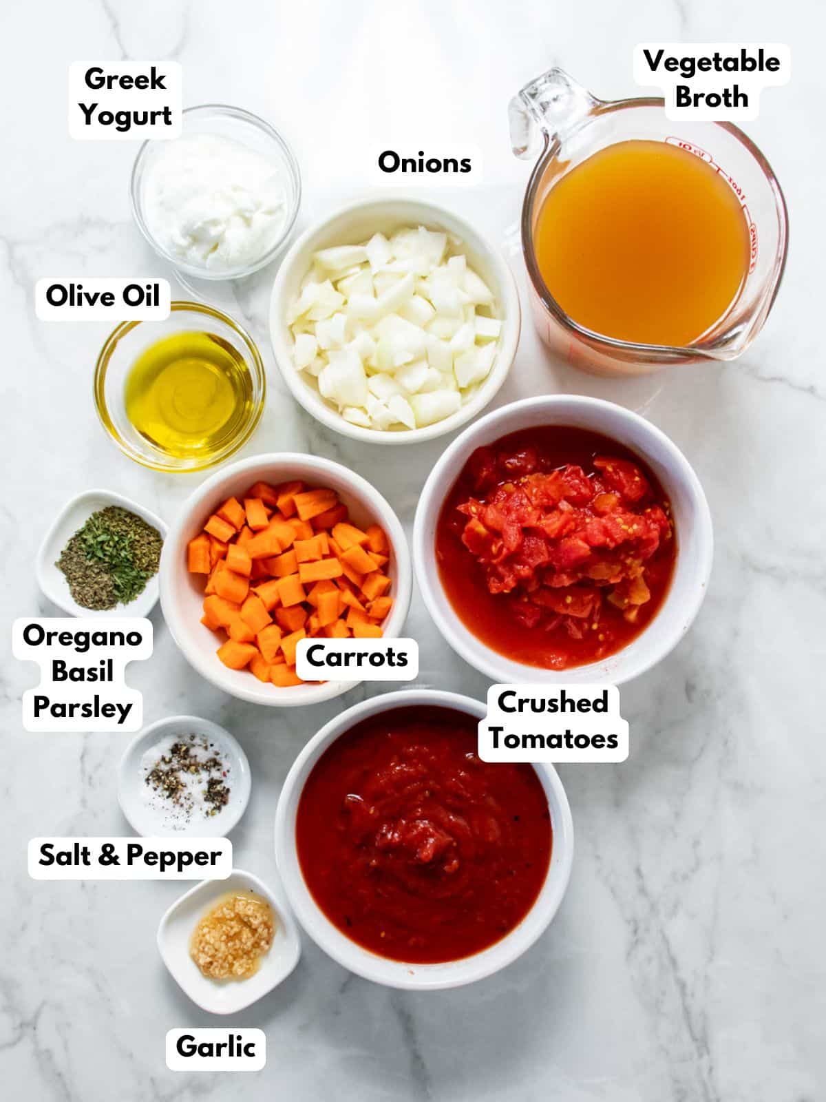 Ingredients to make healthy tomato soup on the table with labels to identify them.