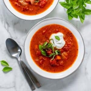 A bowl of healthy tomato soup topped with Greek yogurt and basil.