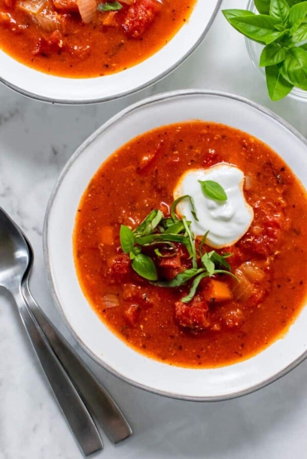 A bowl of healthy tomato soup topped with Greek yogurt and basil.