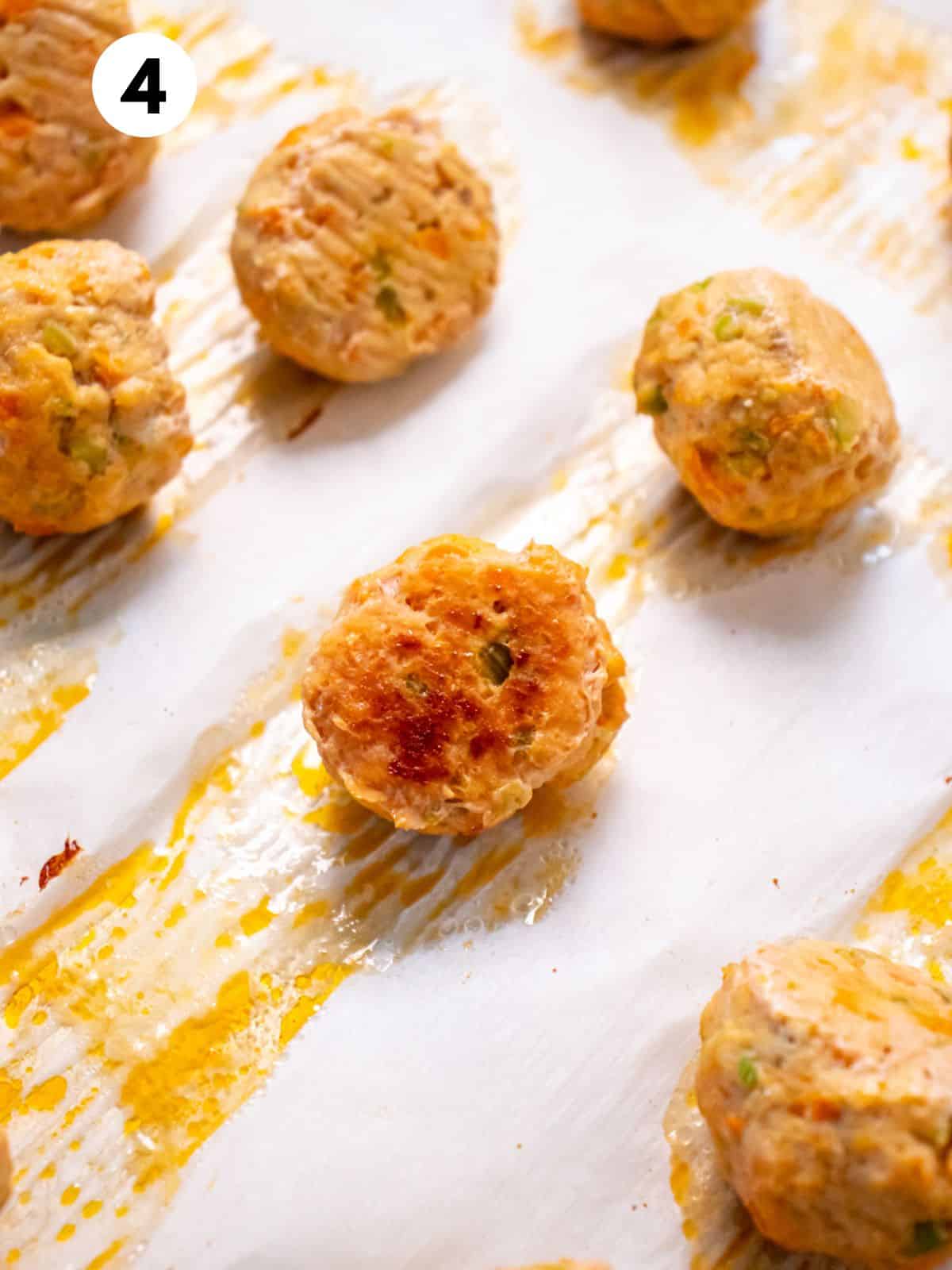 Cooked buffalo chicken meatballs on a baking tray.