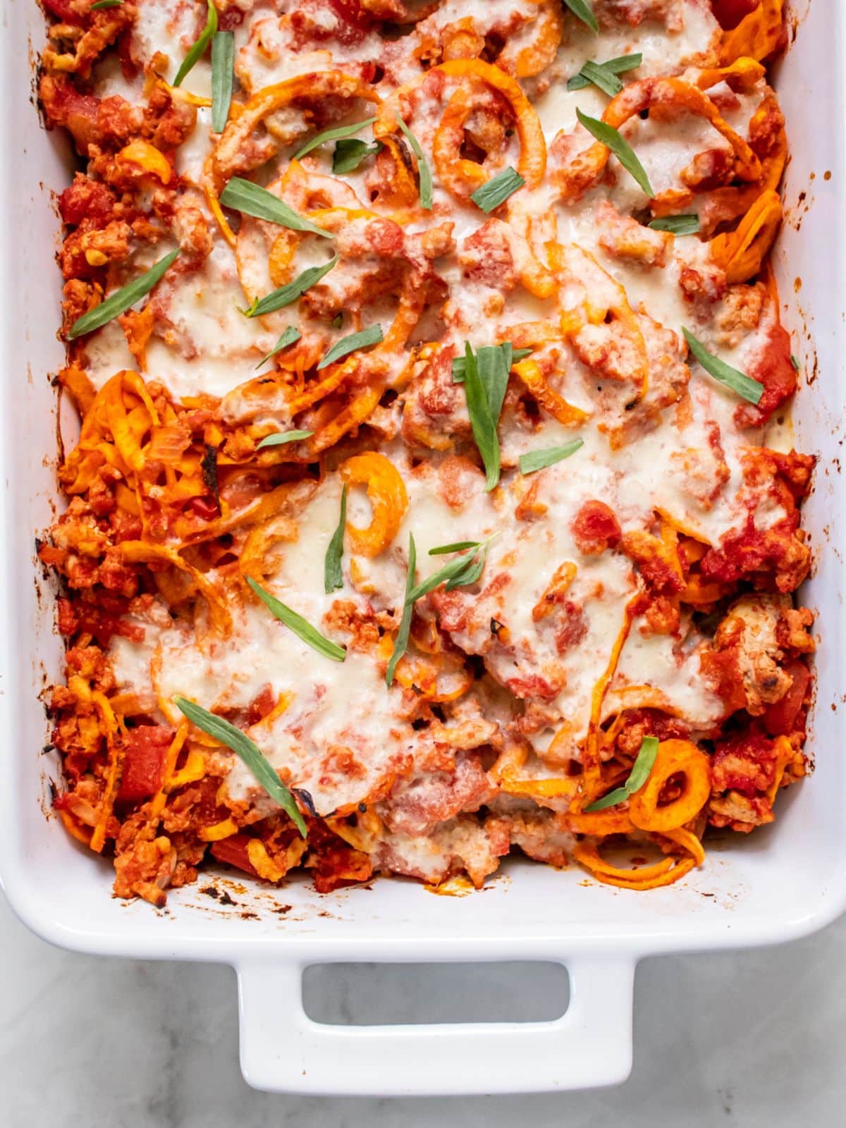 A casserole dish of ground turkey casserole garnished with tarragon.