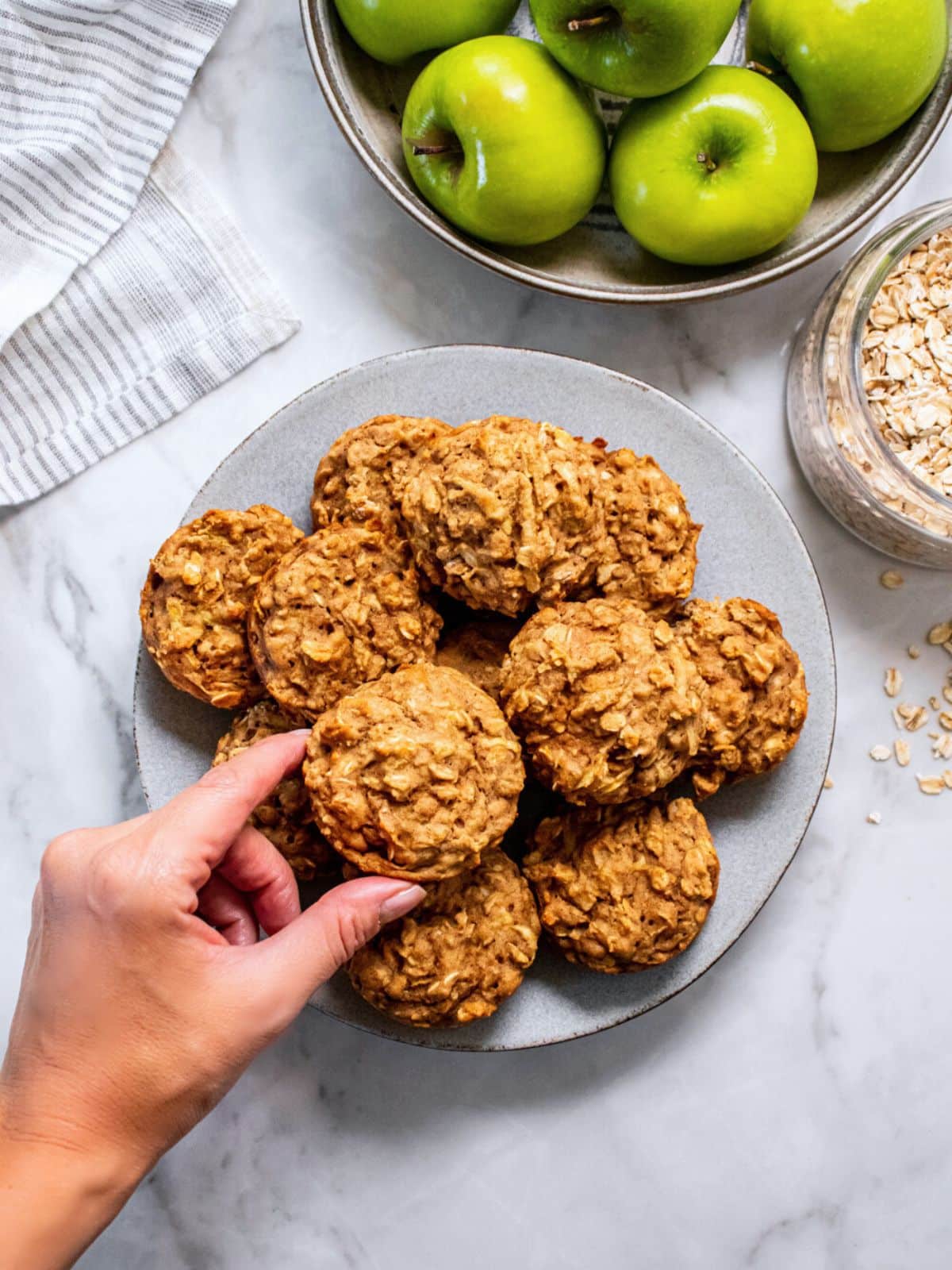 A plate of healthy apple muffins next to a bowl of green apples.