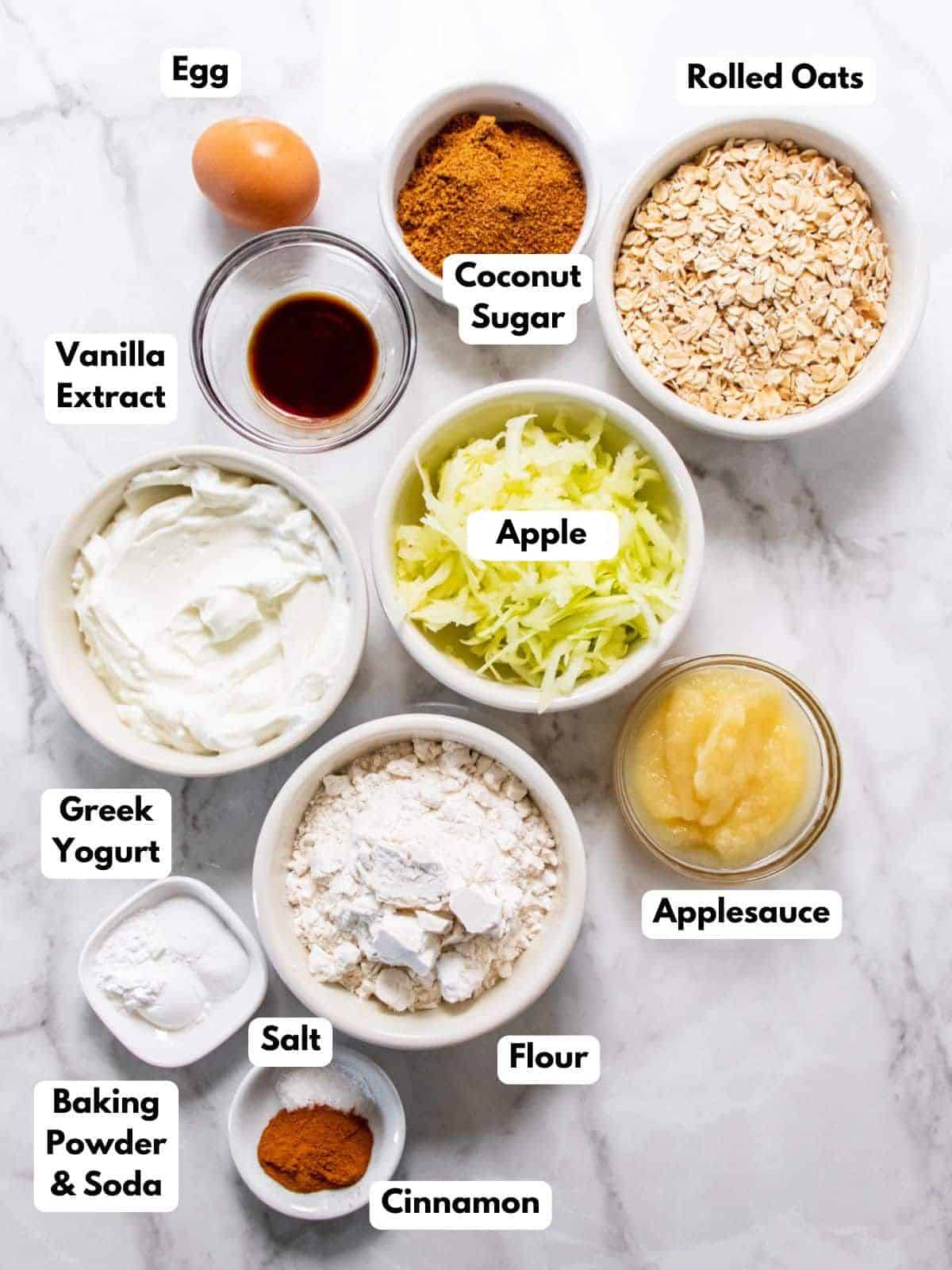 Healthy apple muffin ingredients on the table in bowls with labels to identify each one.