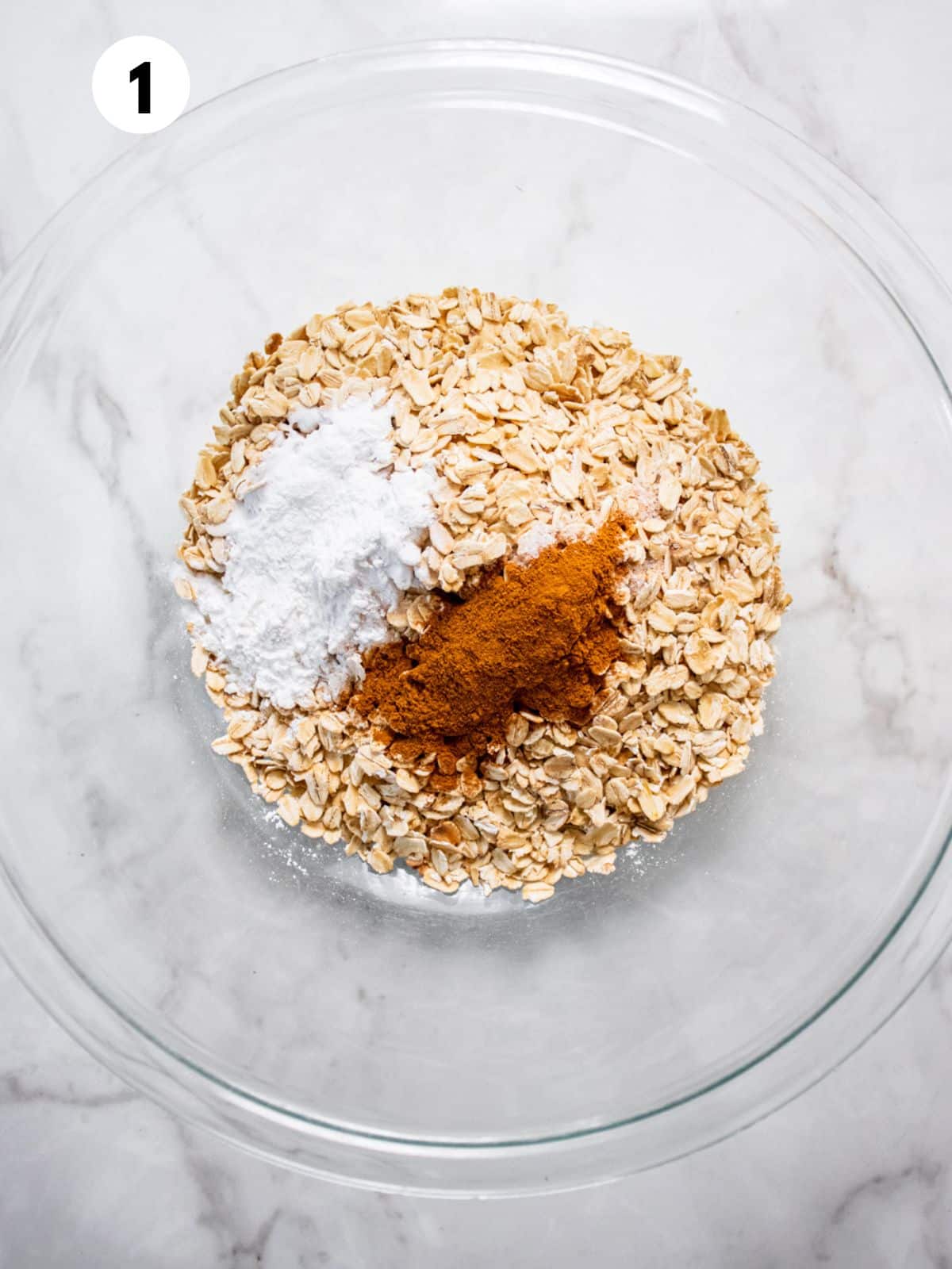 Oatmeal, cinnamon and baking powder in a glass bowl.