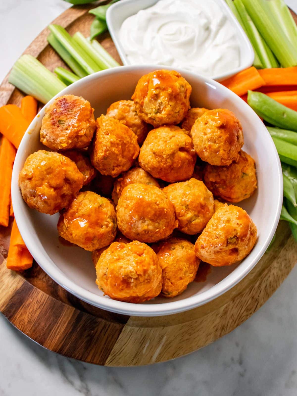A bowl of healthy buffalo chicken meatballs on a platter.