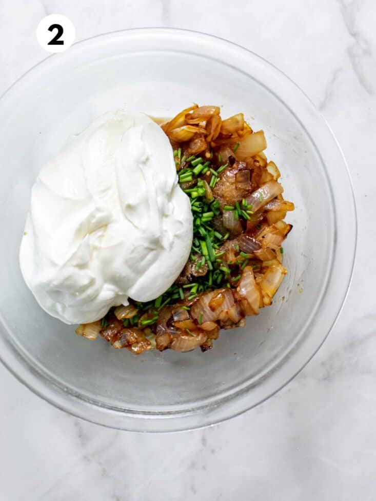 Caramelized onions in a bowl with seasonings and Greek yogurt.