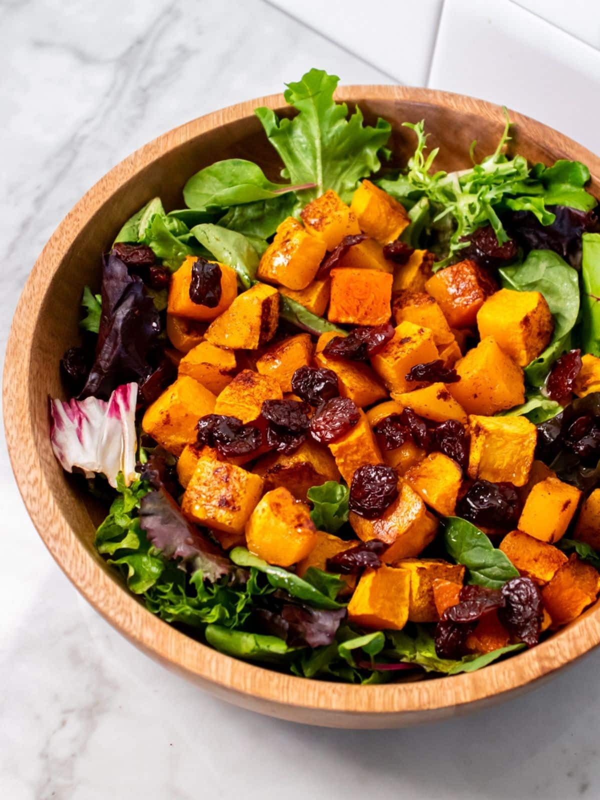 Butternut squash salad in a wooden bowl, ready to be served.