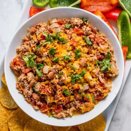 A bowl of crockpot chili cheese dip on the table.