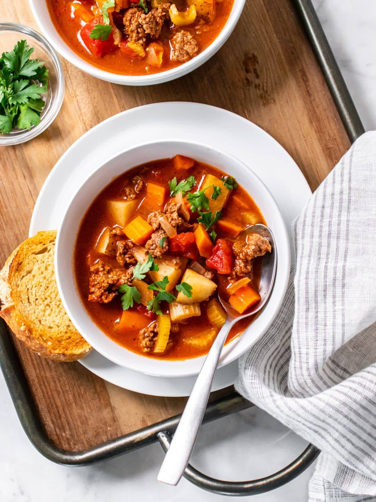 A bowl of old-fashioned beef vegetable soup with a spoon resting in a bowl.