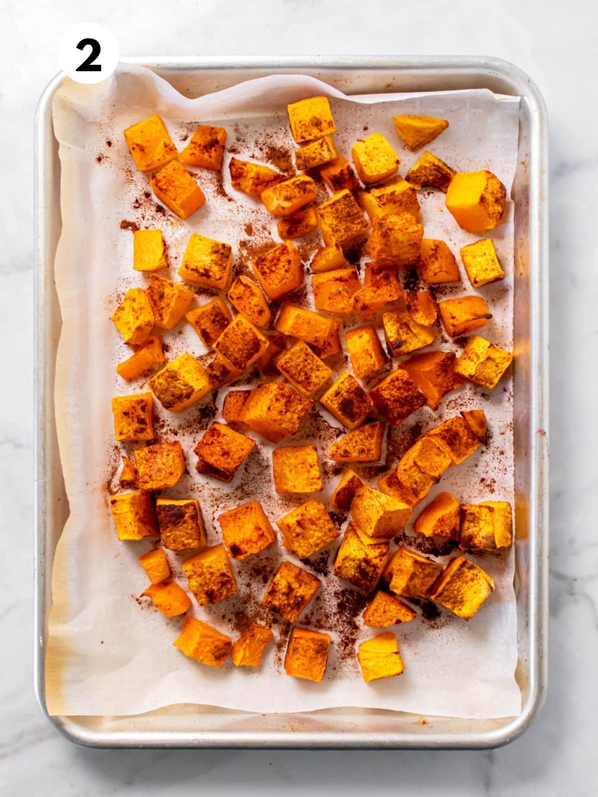 Roasted butternut squash on a parchment-lined baking tray.