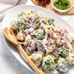 A platter of healthy broccoli and cauliflower salad with a wooden spoon to the side.