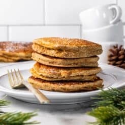 A stack of gingerbread pancakes on the table with a fork to the side.