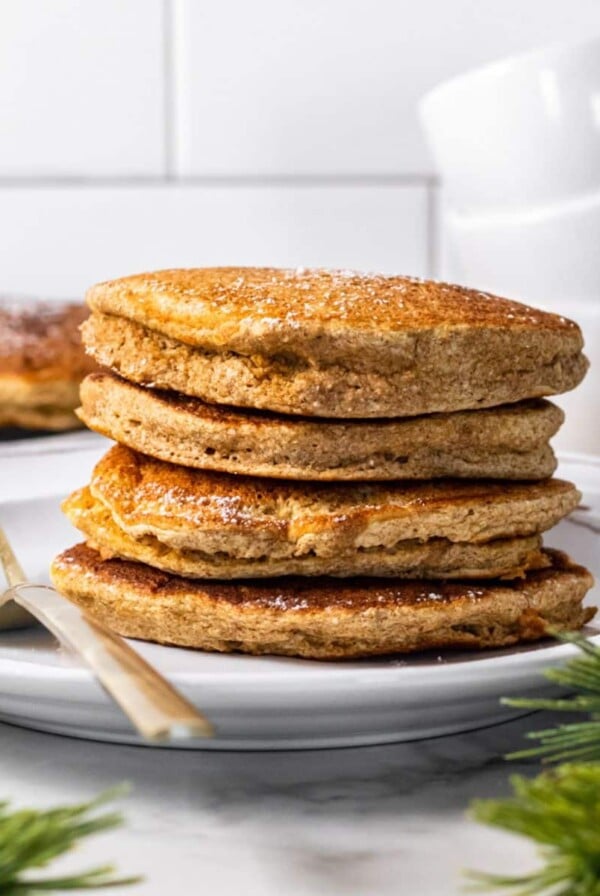 A stack of gingerbread pancakes on the table with a fork to the side.