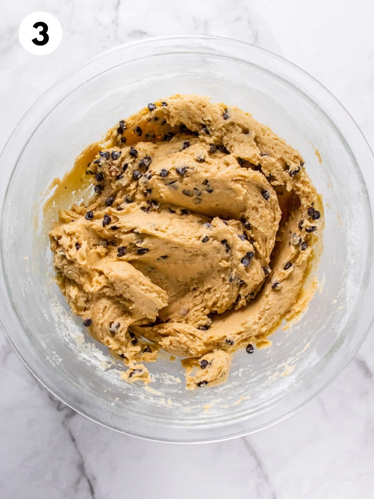 A glass bowl containing the combined batter for healthy chocolate chip cookie bars.