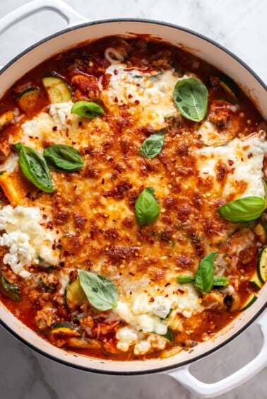A skillet of healthy lasagna recipe on the table garnished with fresh basil.