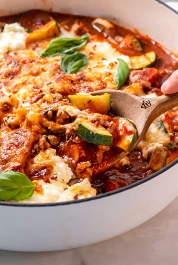 A skillet of healthy lasagna without noodles with a spoon scooping up some.
