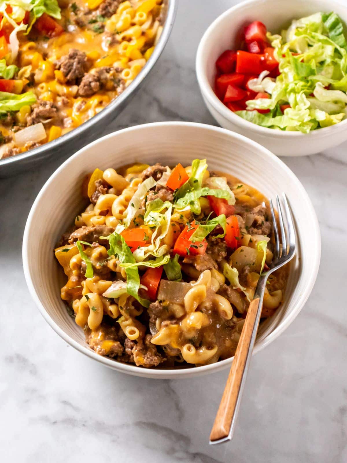 Beef mac and cheese in a bowl with a fork on the side.