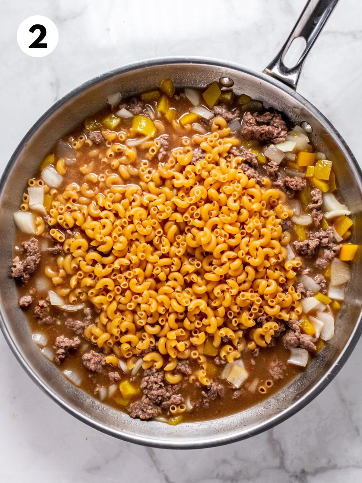 Broth and macaroni added to the skillet with the beef.