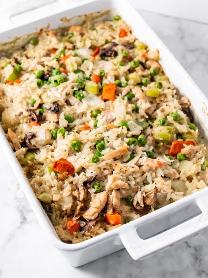 white rectangular casserole dish with peas, carrots, chicken and rice