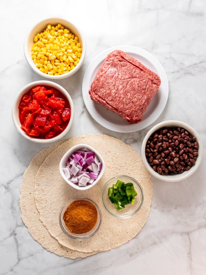 white counter with bowls of ingredients and a plate of ground beef