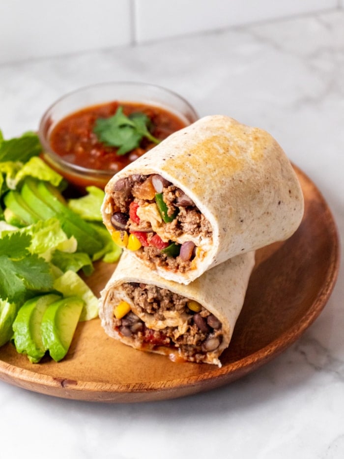 two burritos on top of each other on a brown plate