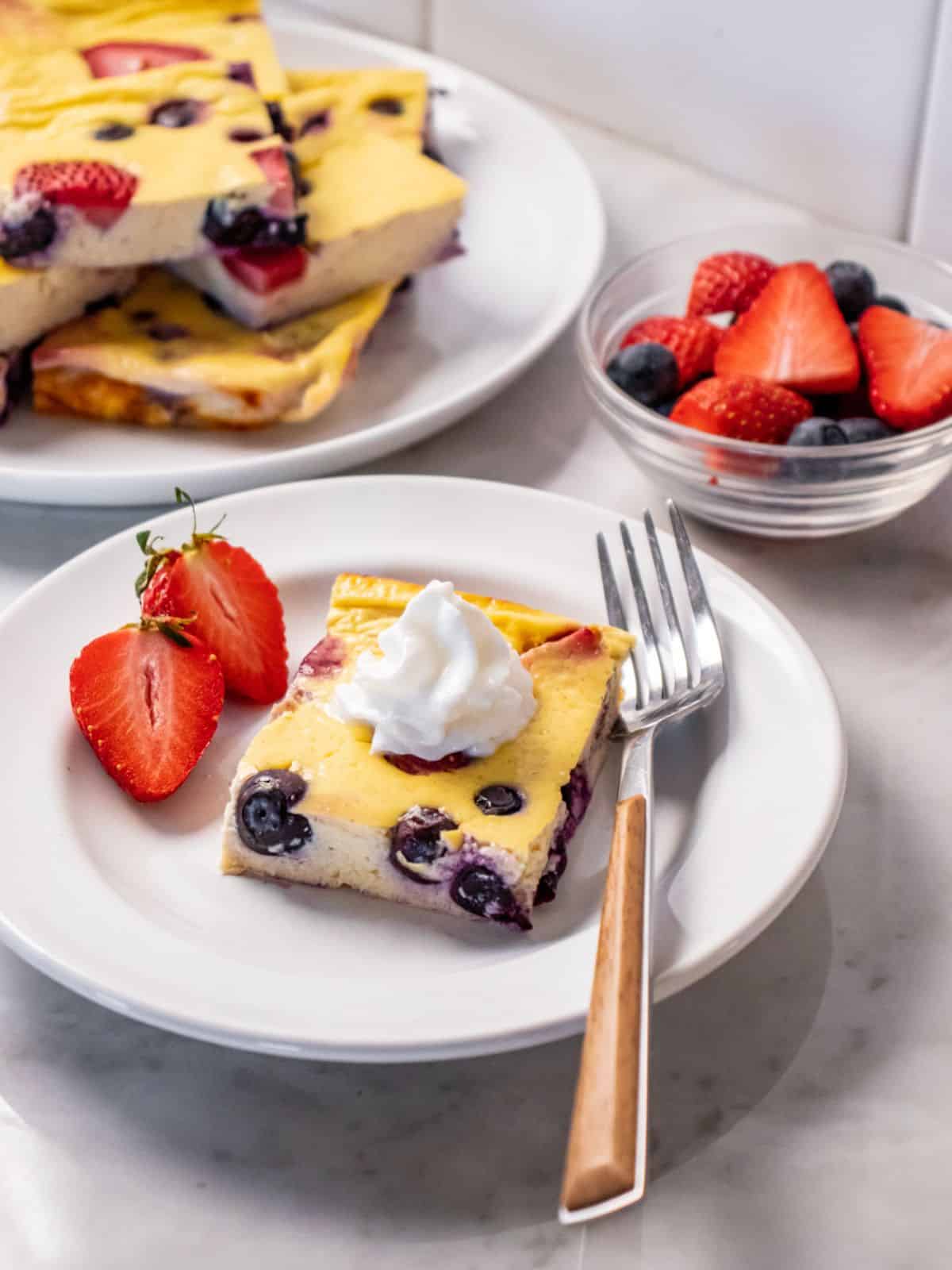 yogurt bake on a white plate with a fork and sliced strawberries