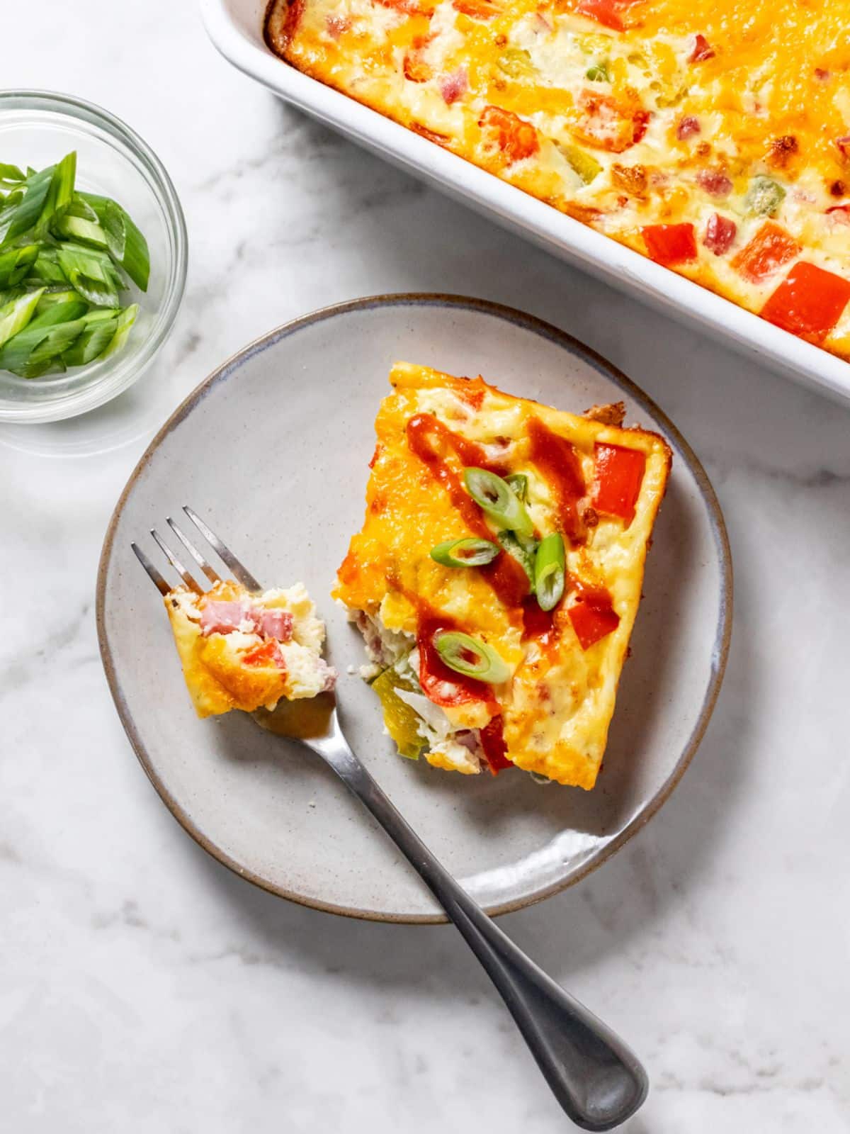 A slice of omelet casserole with a fork on a silver plate.