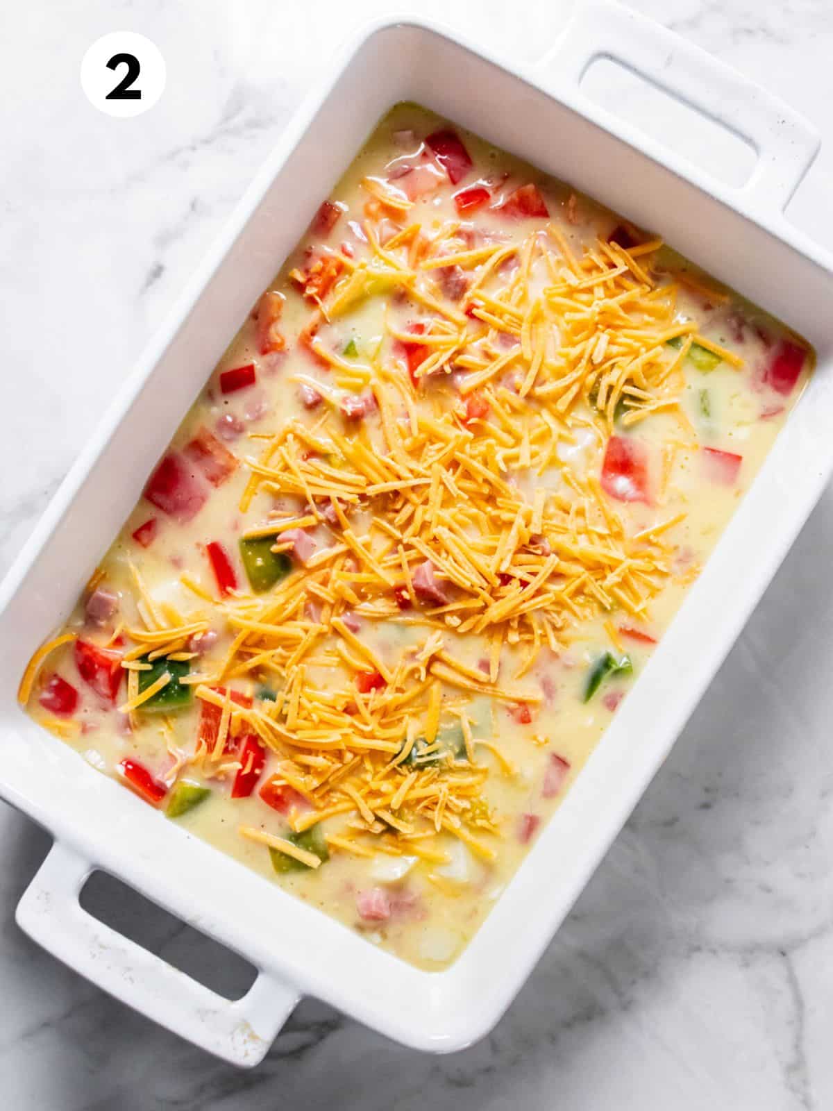 Egg mixture poured into a casserole dish and topped with cheese.