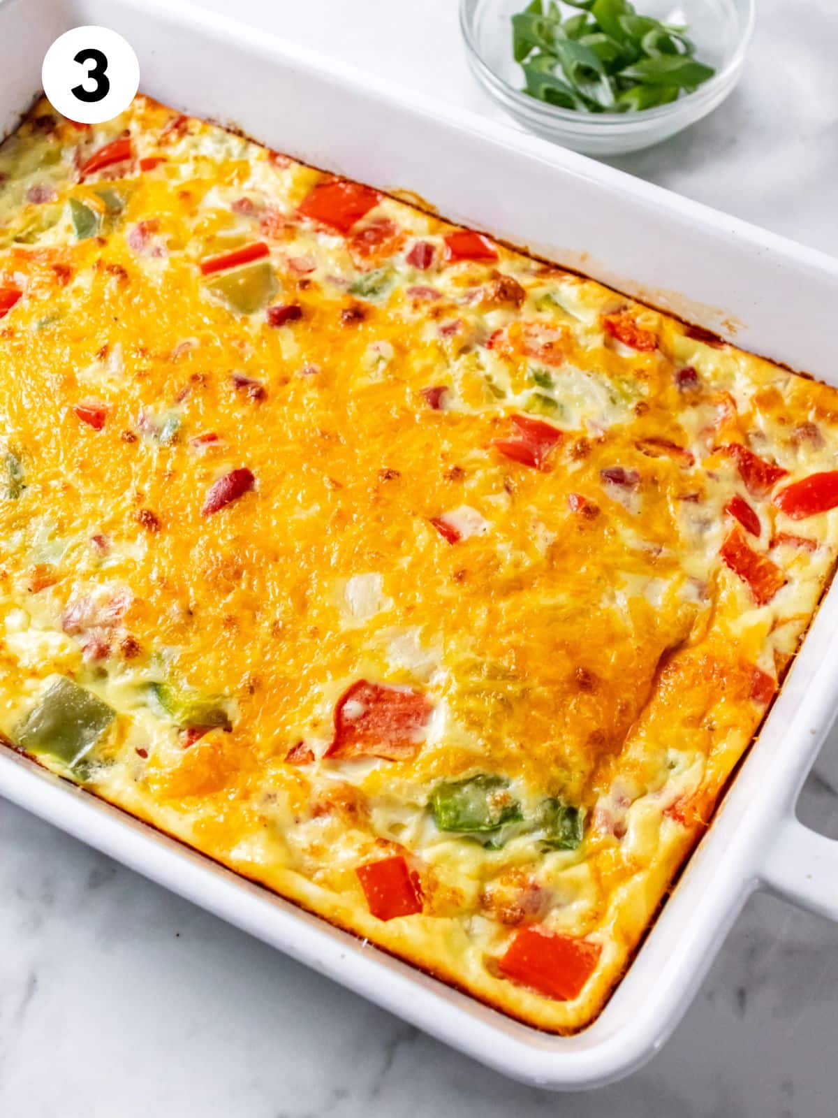 Ham and vegetable omelet casserole baked in a white dish.