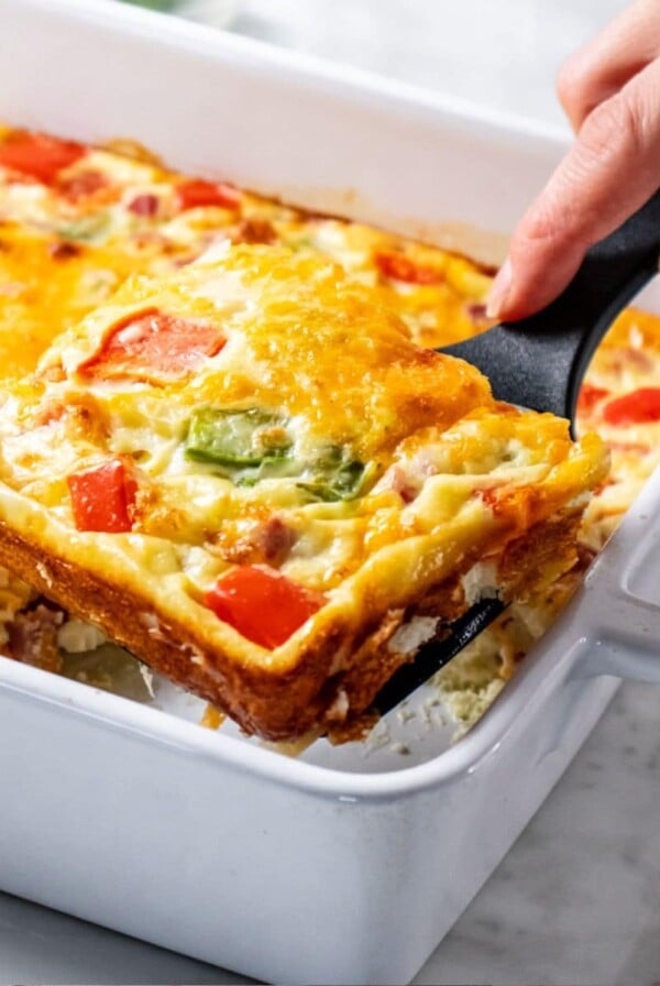 A spatula lifting up a slice of Denver omelete casserole.