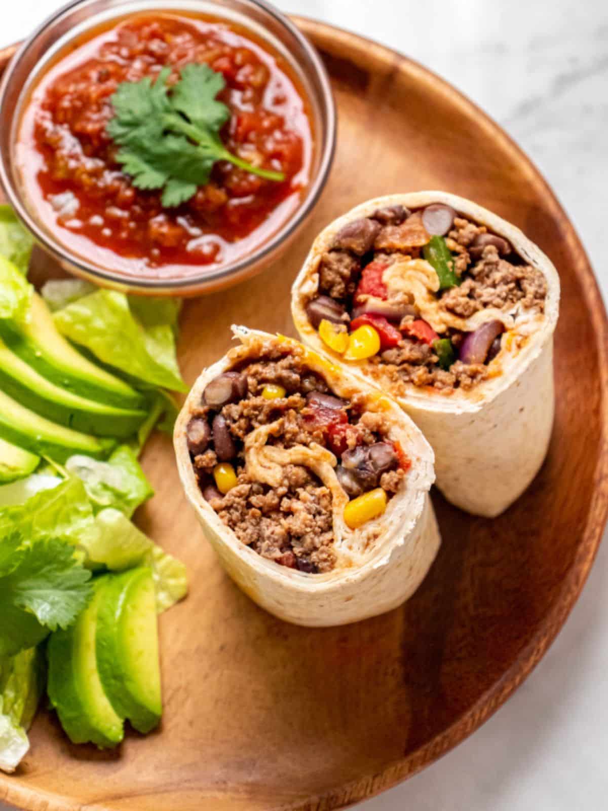 A high protein beef burrito on a plate with a side of salsa.