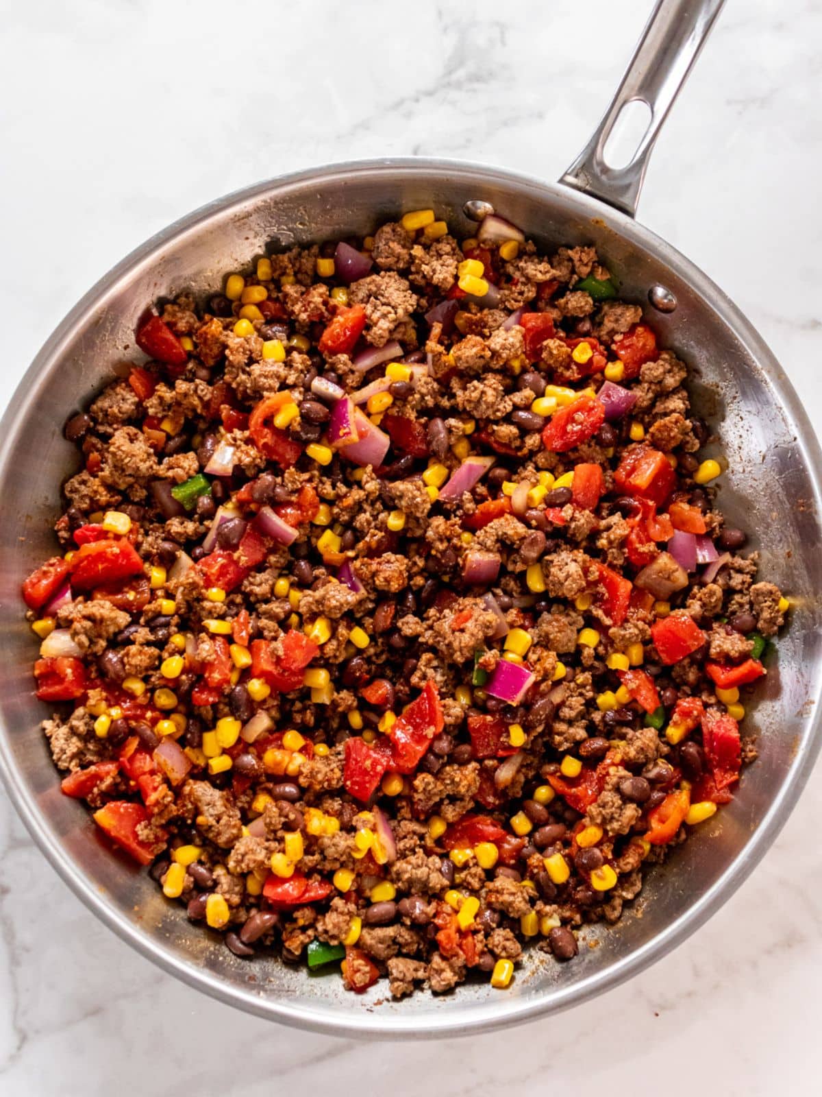 Black beans and tomatoes added to the skillet.