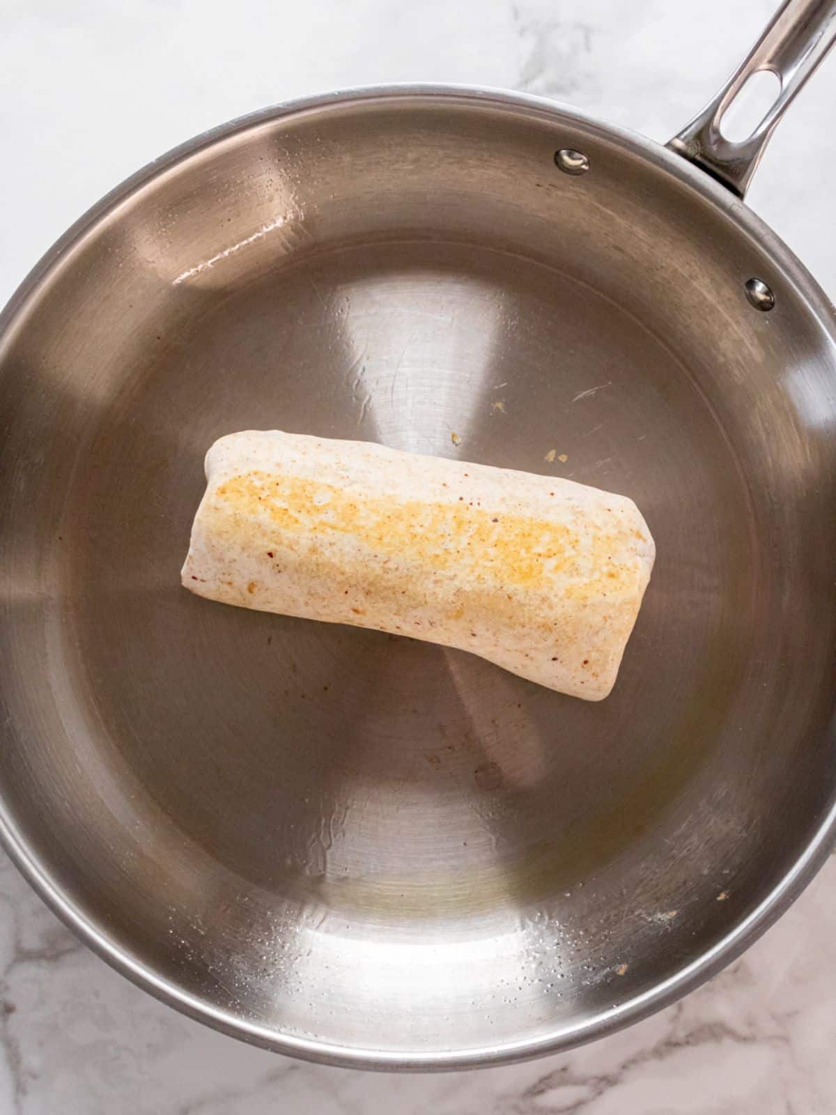 Cooking a high protein burrito in a skillet.
