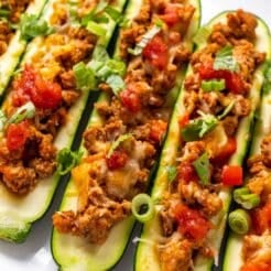 two zucchini boats stuffed with ground turkey on a brown plate with a fork