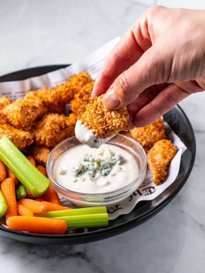 chicken nugget being dipped into blue cheese dressing