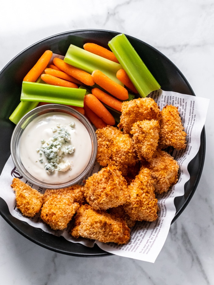 chicken nuggets in a bowl with blue cheese dressing, carrots and celery