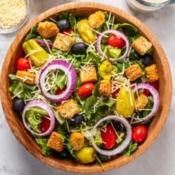 A wooden bowl of healthier copycat Olive Garden salad on the table.
