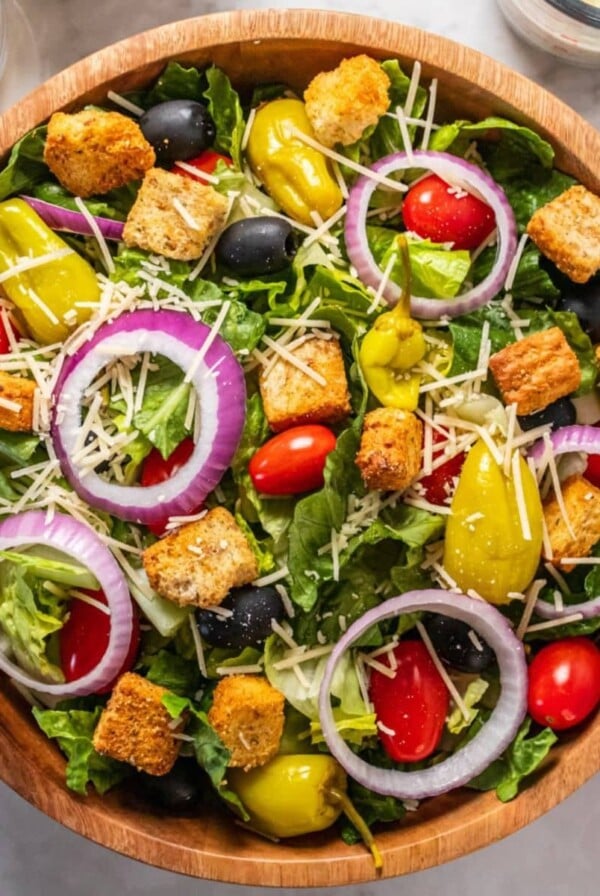 A wooden bowl of healthier copycat Olive Garden salad on the table.