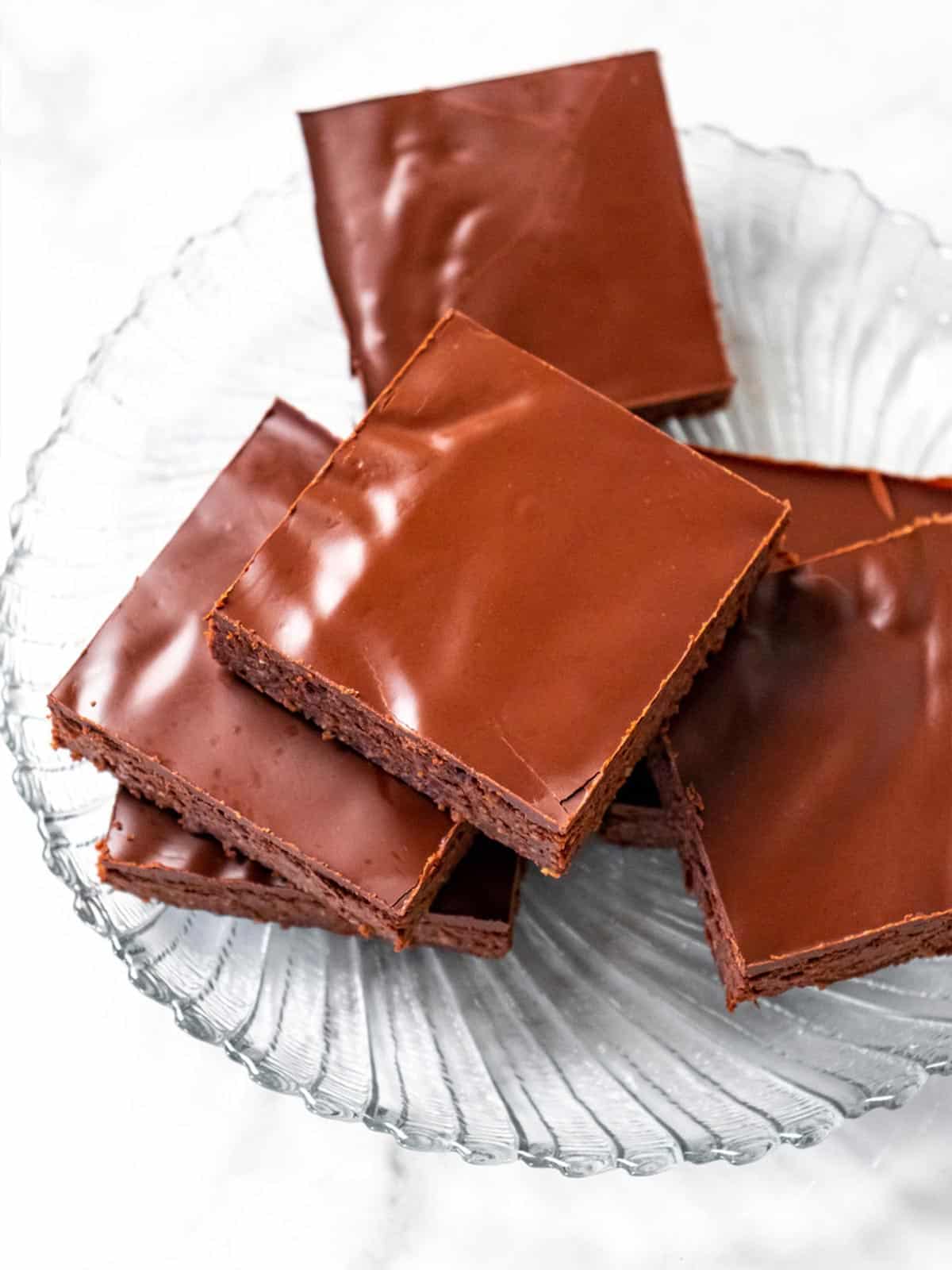 Healthy chocolate brownies on a clear glass plate stacked on top of each other in different angles.